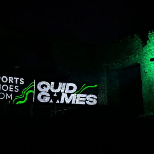 SportsShoes.com and Quid Games logo projected on Kendal Castle